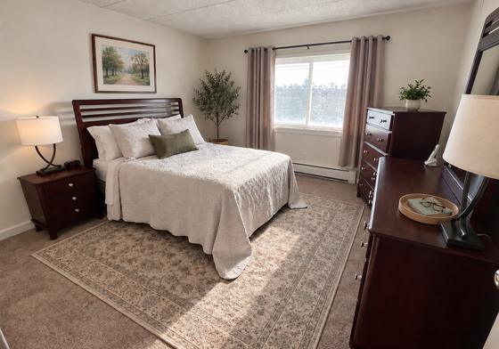 Furnished bedroom with cream bedding in a J.E. apartment